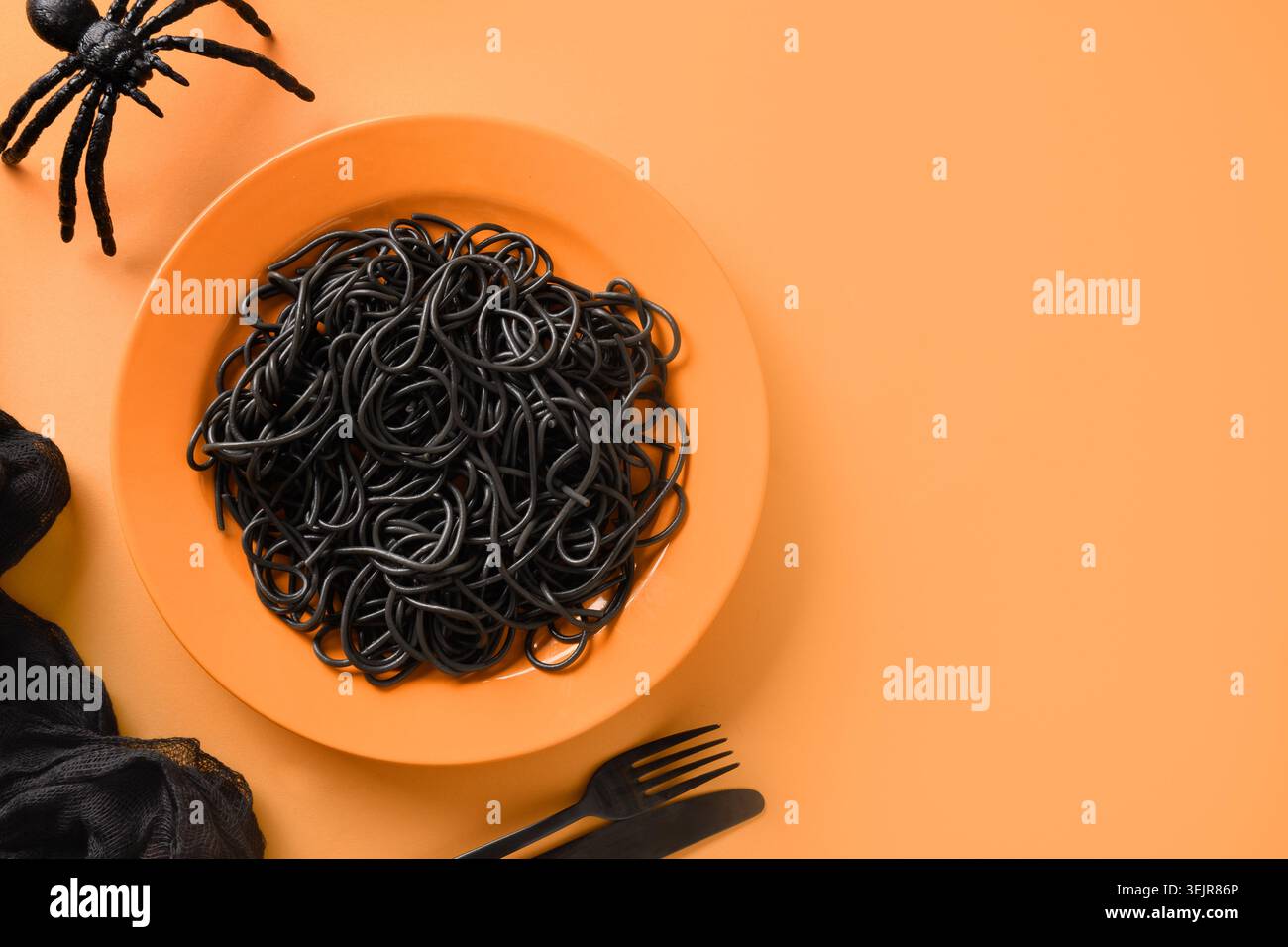 Halloween Italian black pasta decorated funny spiders in orange plate . Stock Photo