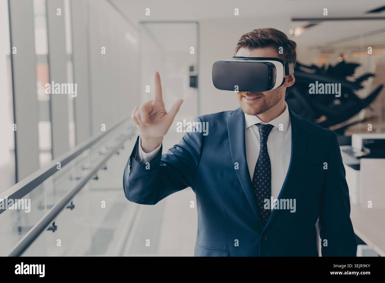 Business man using virtual reality headset in modern office hallway Stock Photo