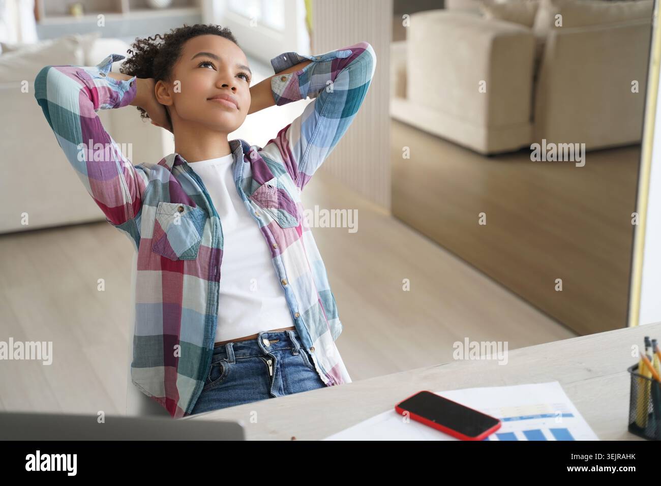 Young black woman taking break at desk while working from home Stock Photo