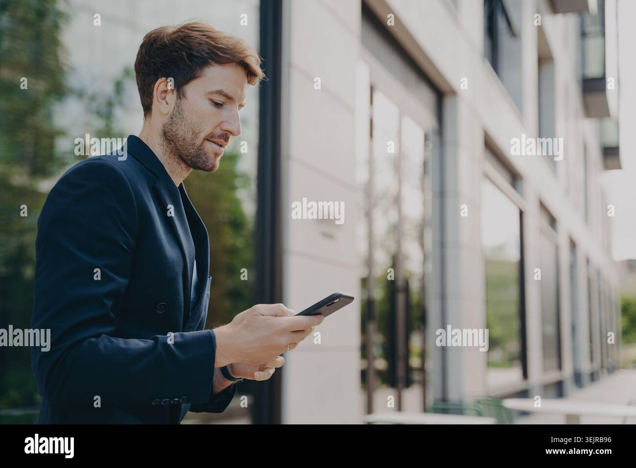 Professional Man Using Smartphone Outside Modern Office Building Checking Messages Stock Photo