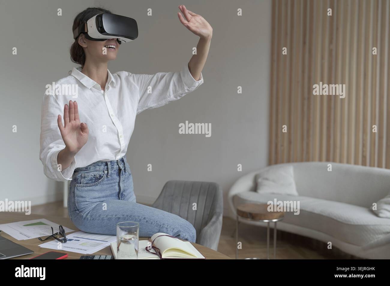Young woman uses VR headset and gestures in modern home office Stock Photo
