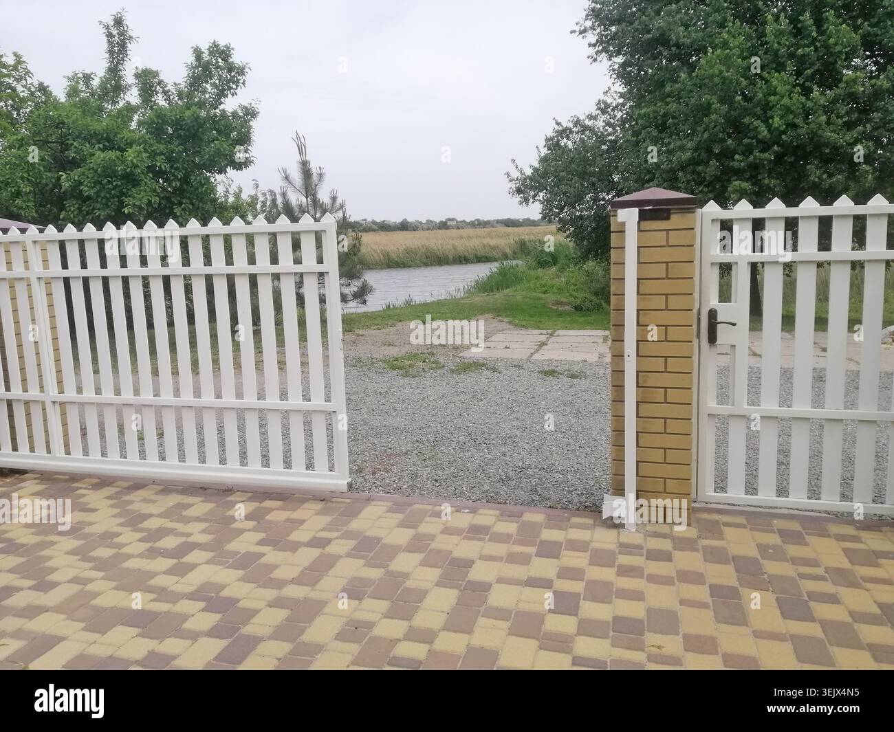 Column Fence Gate White picket fence with brick columns stands in front of rural setting ...