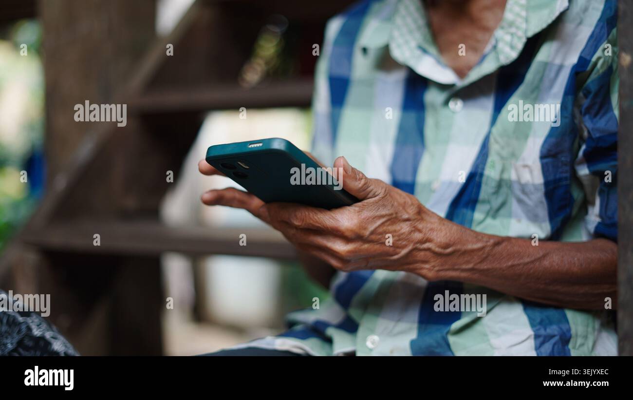 Elderly person's hands holding smartphone, interacting with digital technology Stock Photo
