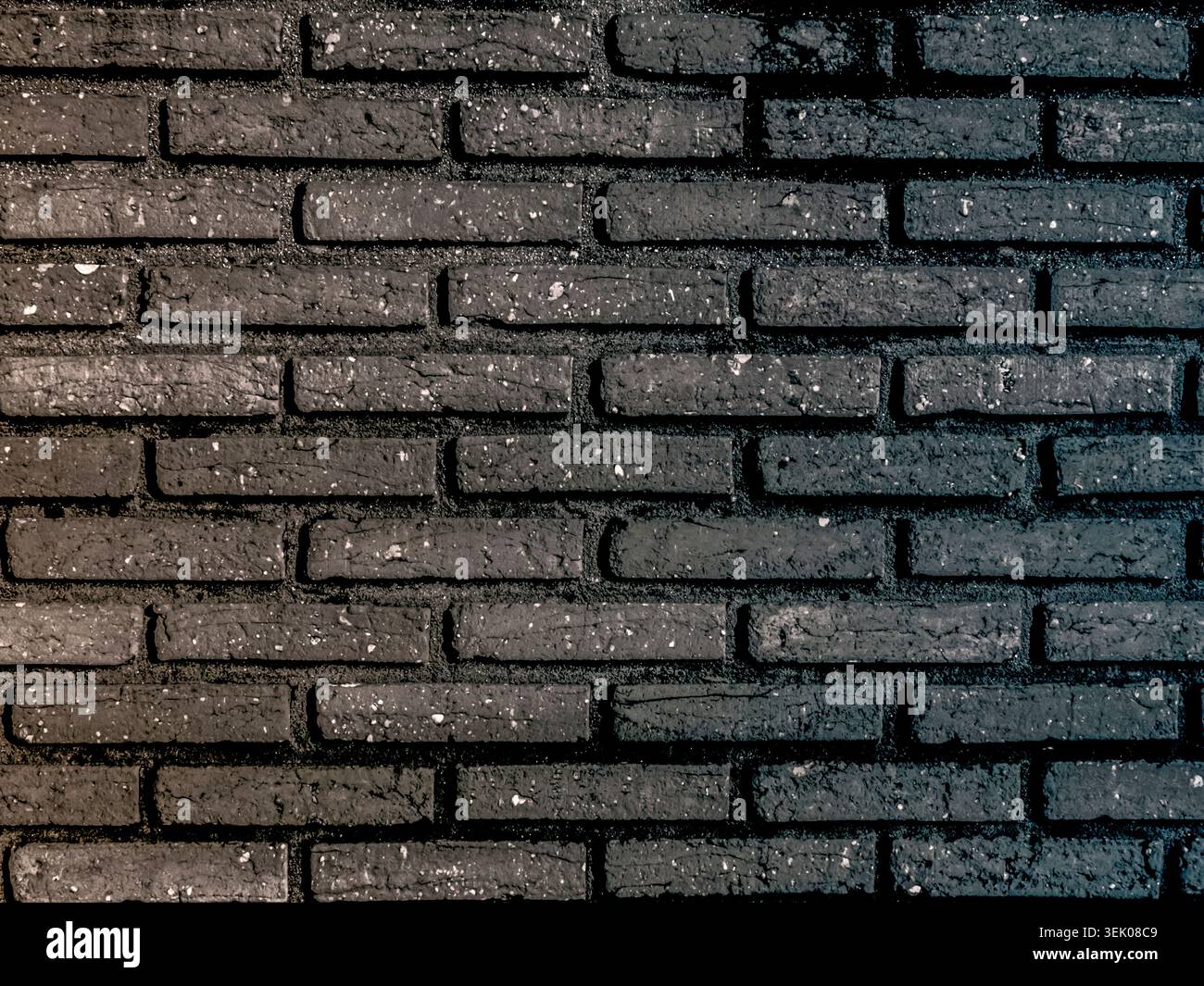 Horizontal view of a modern dark charcoal brick wall. The bricks have a rough, weathered texture with small white flecks, creating a rustic yet contem Stock Photo