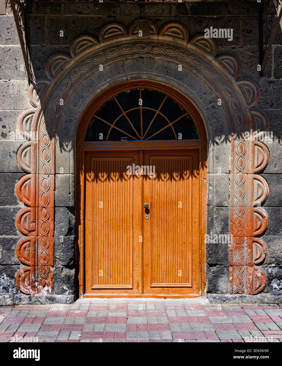 Wooden double doors under stone arch with carved details. Sunlight ...