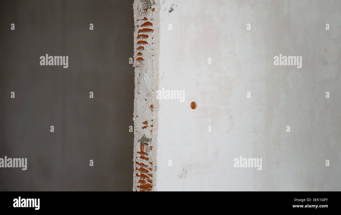 Damaged brick wall with exposed red bricks and crumbling plaster Stock Photo
