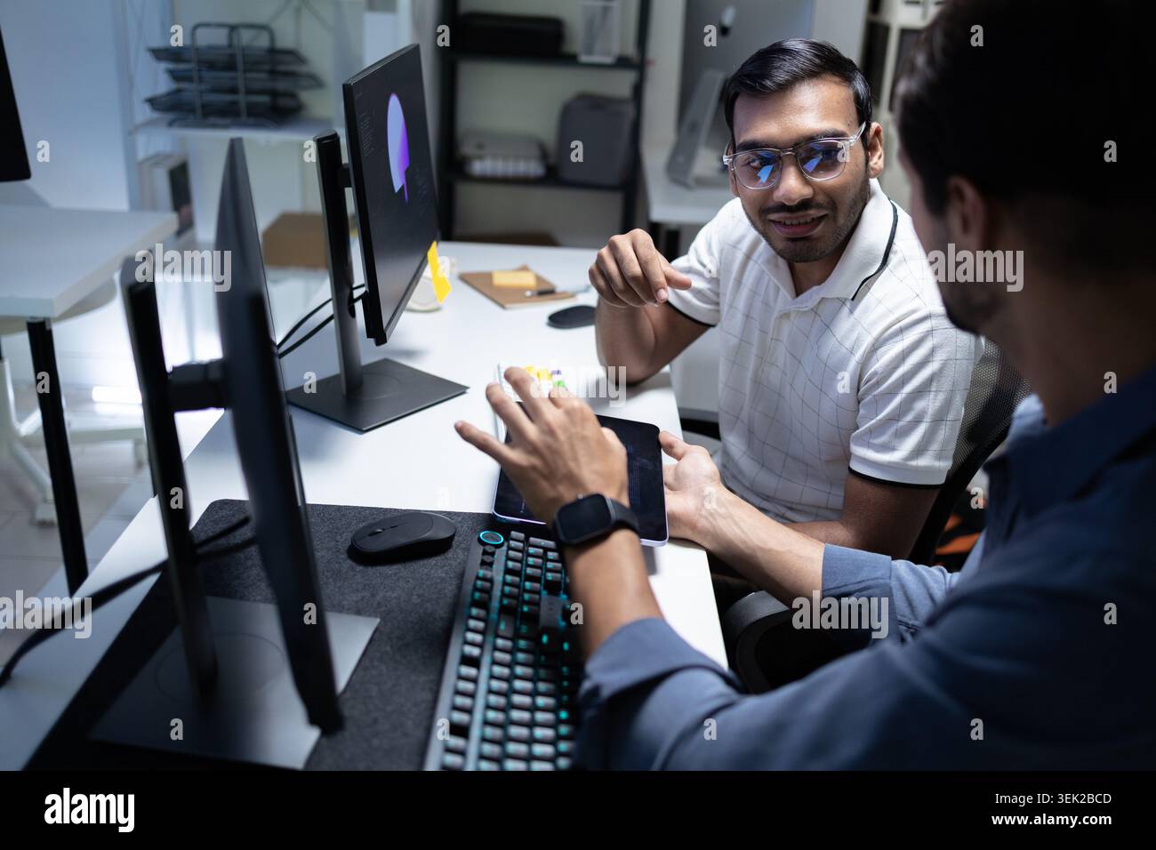 Software Developers Discussing AI Code On Computers In Tech Office Stock Photo