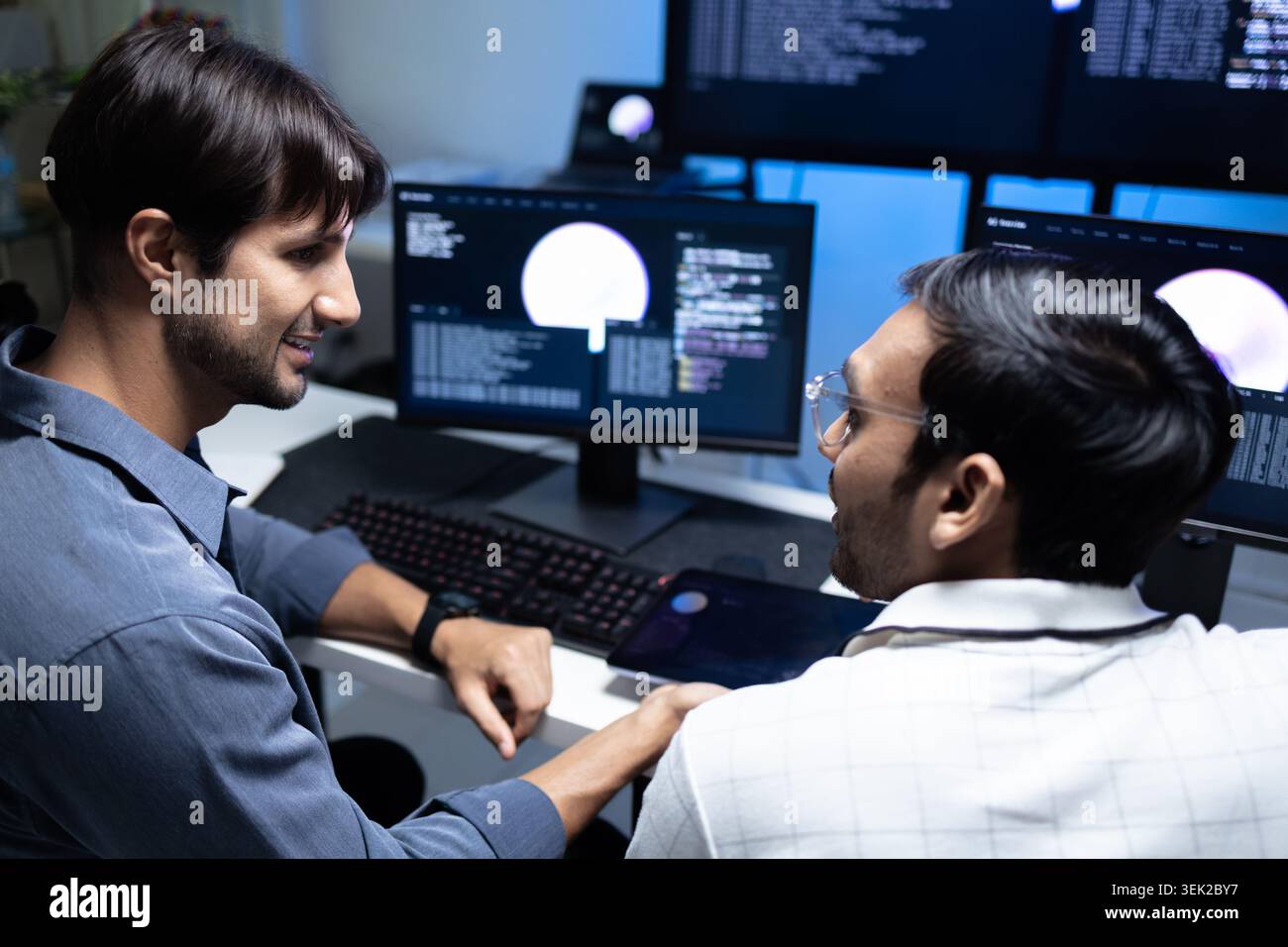 Software Developers Discussing AI Code On Computers In Tech Office Stock Photo
