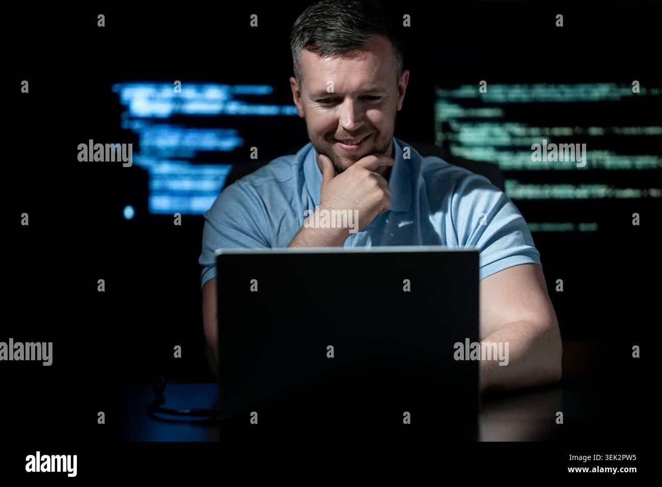 Programmer writes code on laptop. Programmer analyzes system security data. Programmer monitors network activity. Programmer detects cyber attack Stock Photo