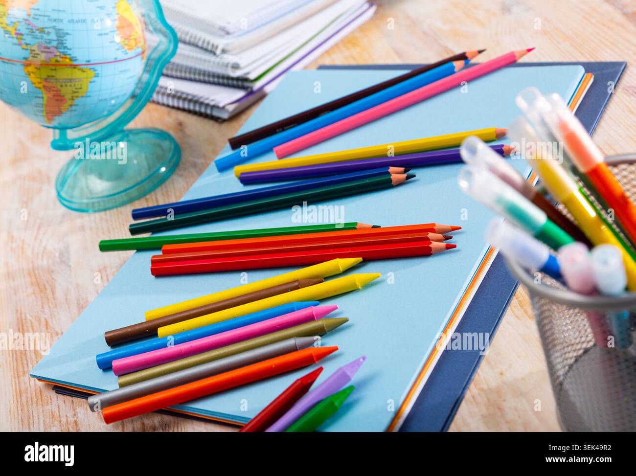 Multicolored pencils on table with papers and notebooks Stock Photo