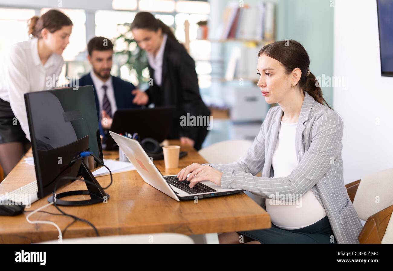 Pregnant woman working on laptop in office Stock Photo
