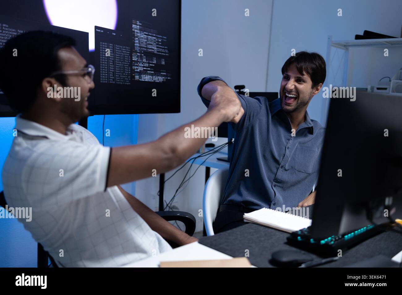 Software Developers Celebrating Success With Fist Bump In Tech Office Stock Photo