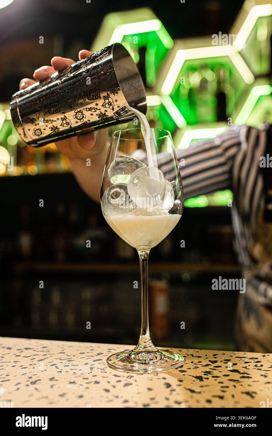 Bartender pouring cocktail into elegant glass Stock Photo