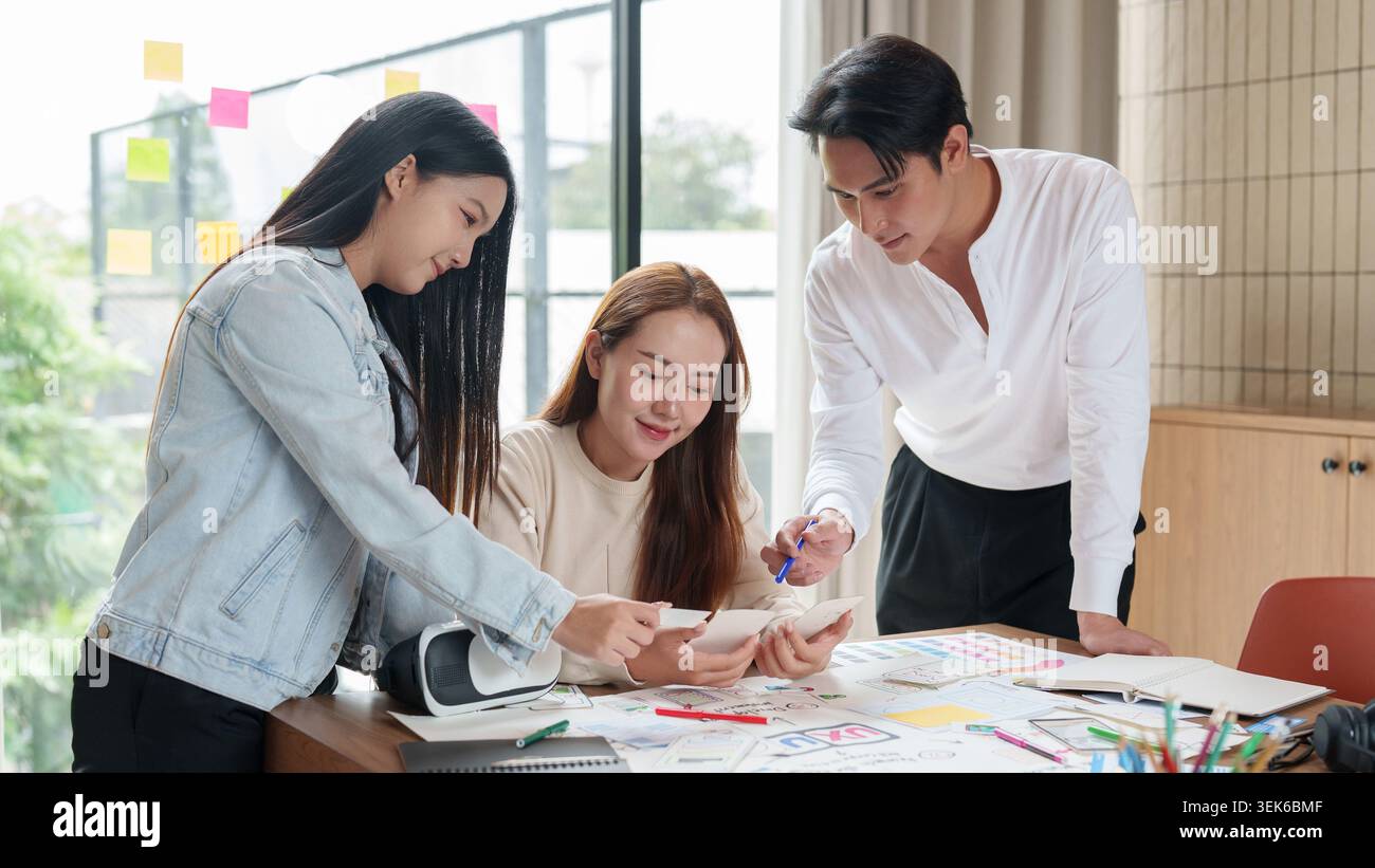 Asian design team collaborating on creative project in modern office Stock Photo