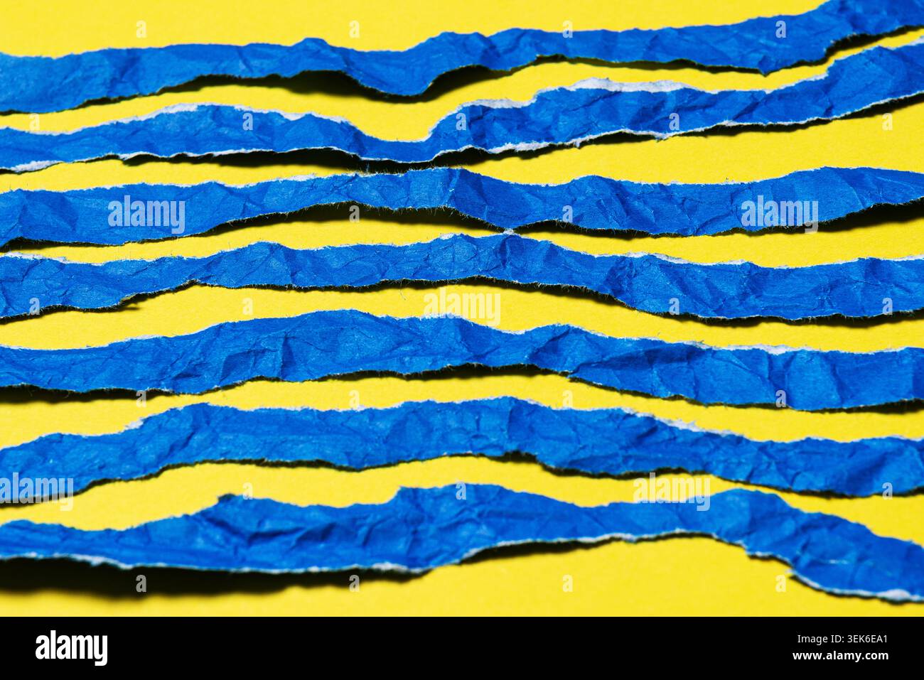 Abstract Textured Torn Blue Paper Strips on Bright Yellow Background Stock Photo
