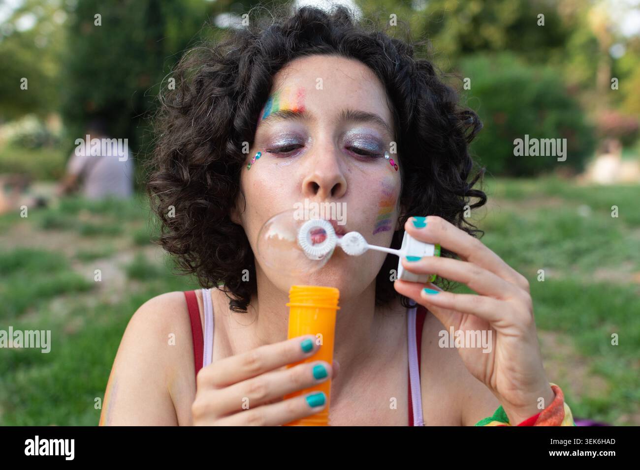 Young woman blowing soap bubbles at pride event Stock Photo