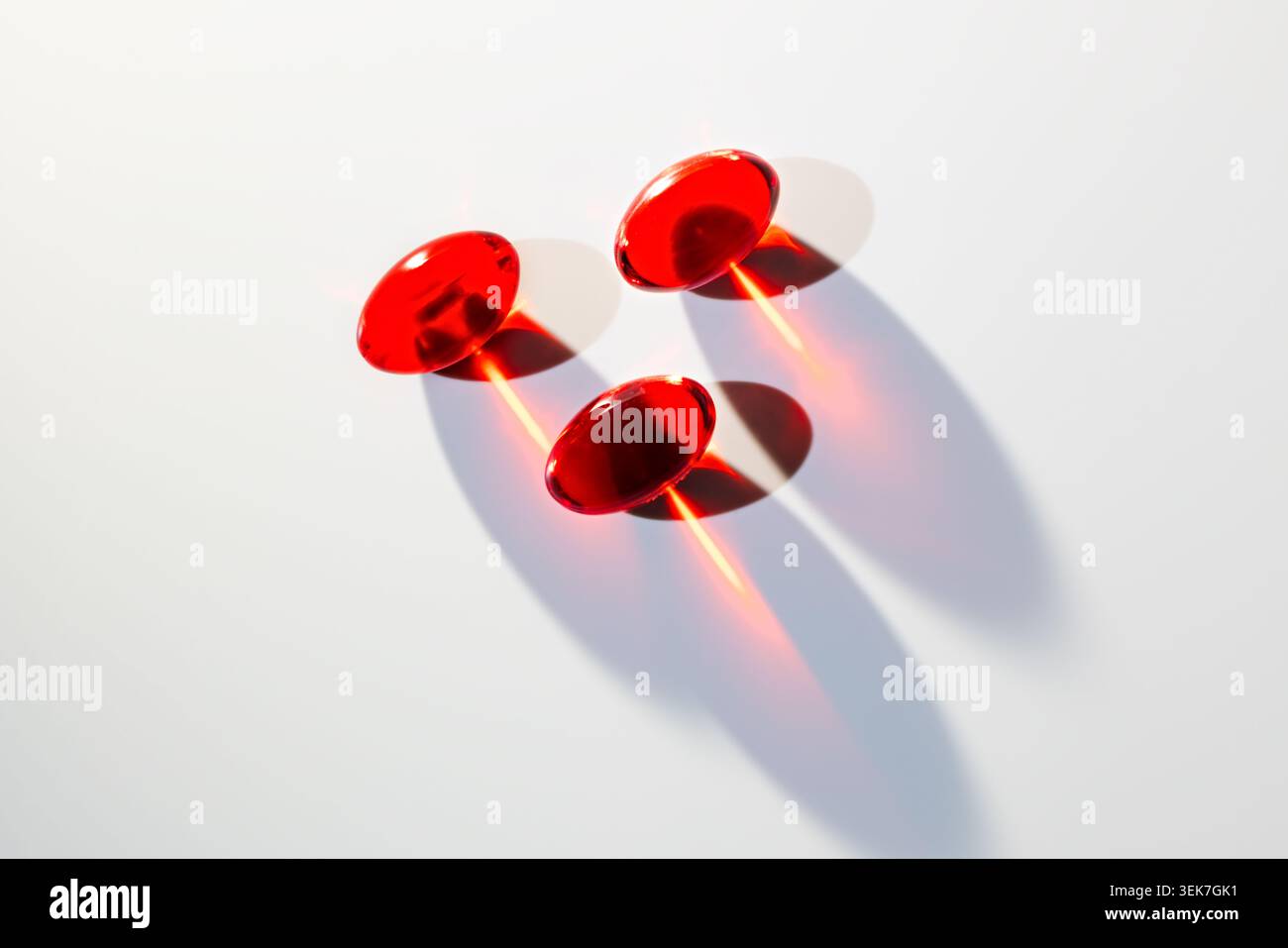 Minimalist Red Translucent Capsules with Dramatic Shadows on White Background Stock Photo