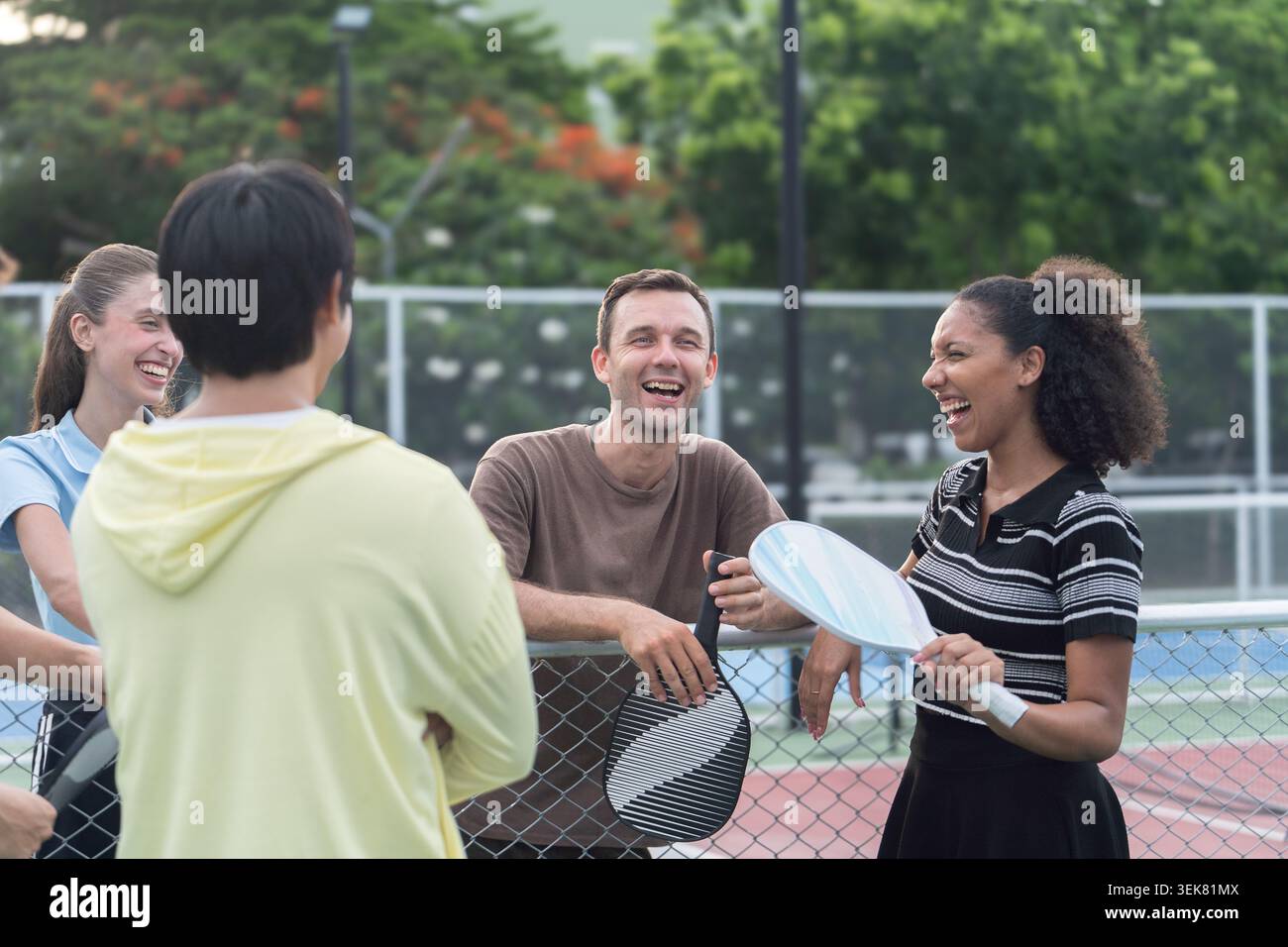 Active Diverse People Playing Pickleball on Outdoor Court Stock Photo