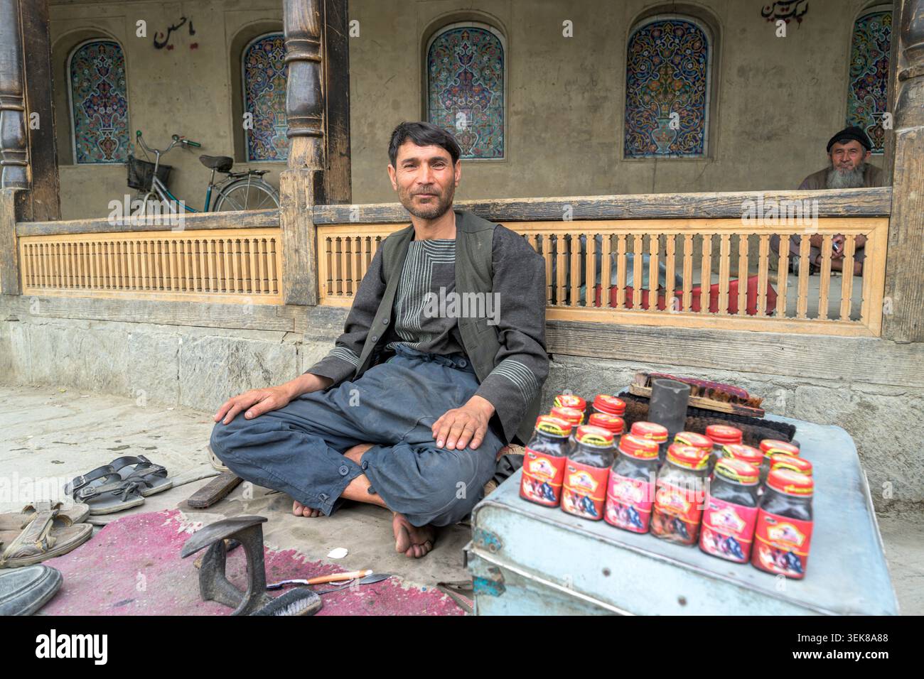 Shoemaker sitting on a street with shoe polish bottles and tools in kabul. Stock Photo