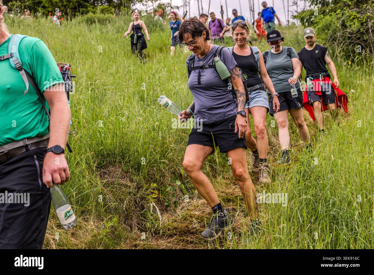 Participants in the 14th Frankenwald Hiking Marathon make their way down a grassy slope. Ludwigsstadt, Bavaria, Germany Stock Photo
