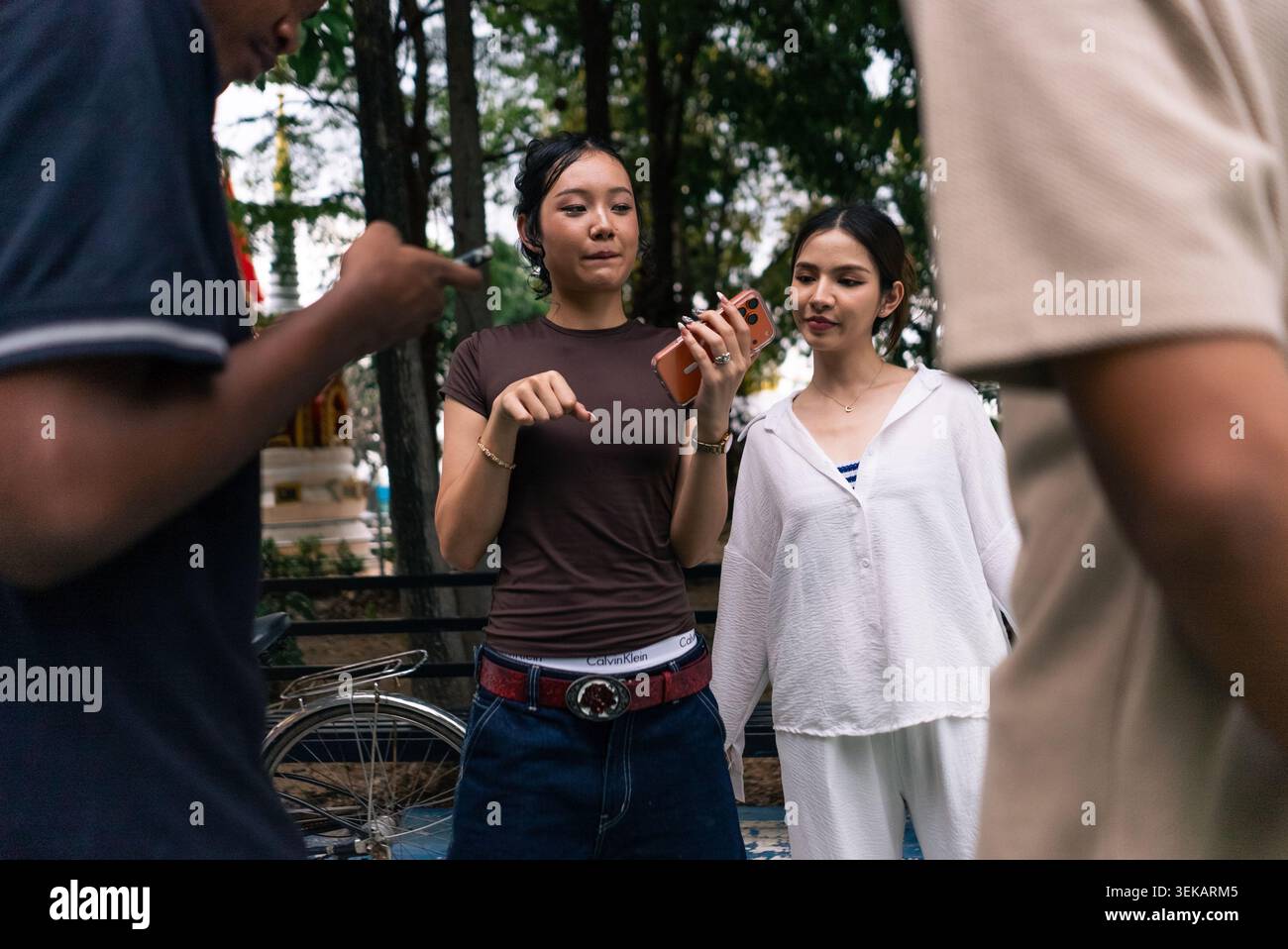 Young friends discussing and sharing information using a smartphone outdoors Stock Photo