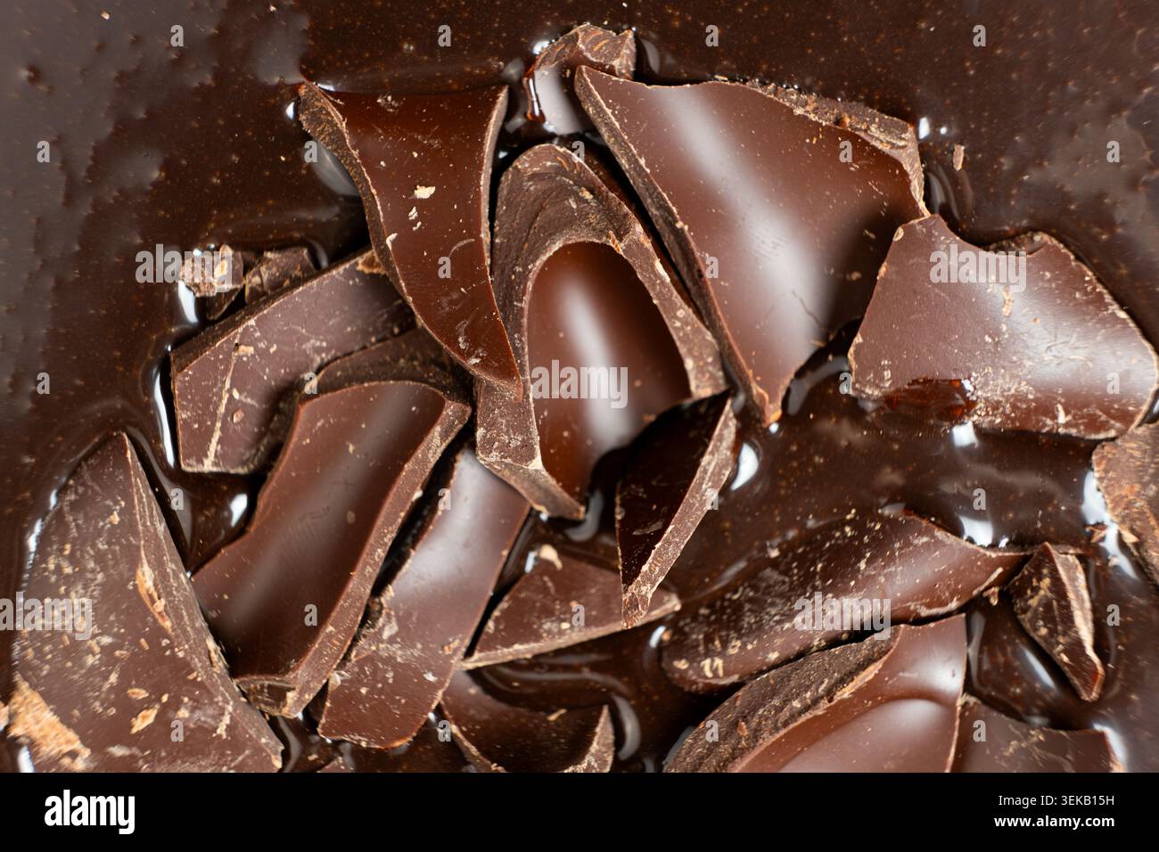 Dark chocolate chunks into liquid melted chocolate sauce background. Stock Photo