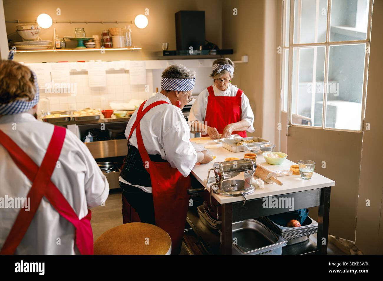 Three senior Caucasian women preparing fresh dough for pastries in a kitchen Stock Photo