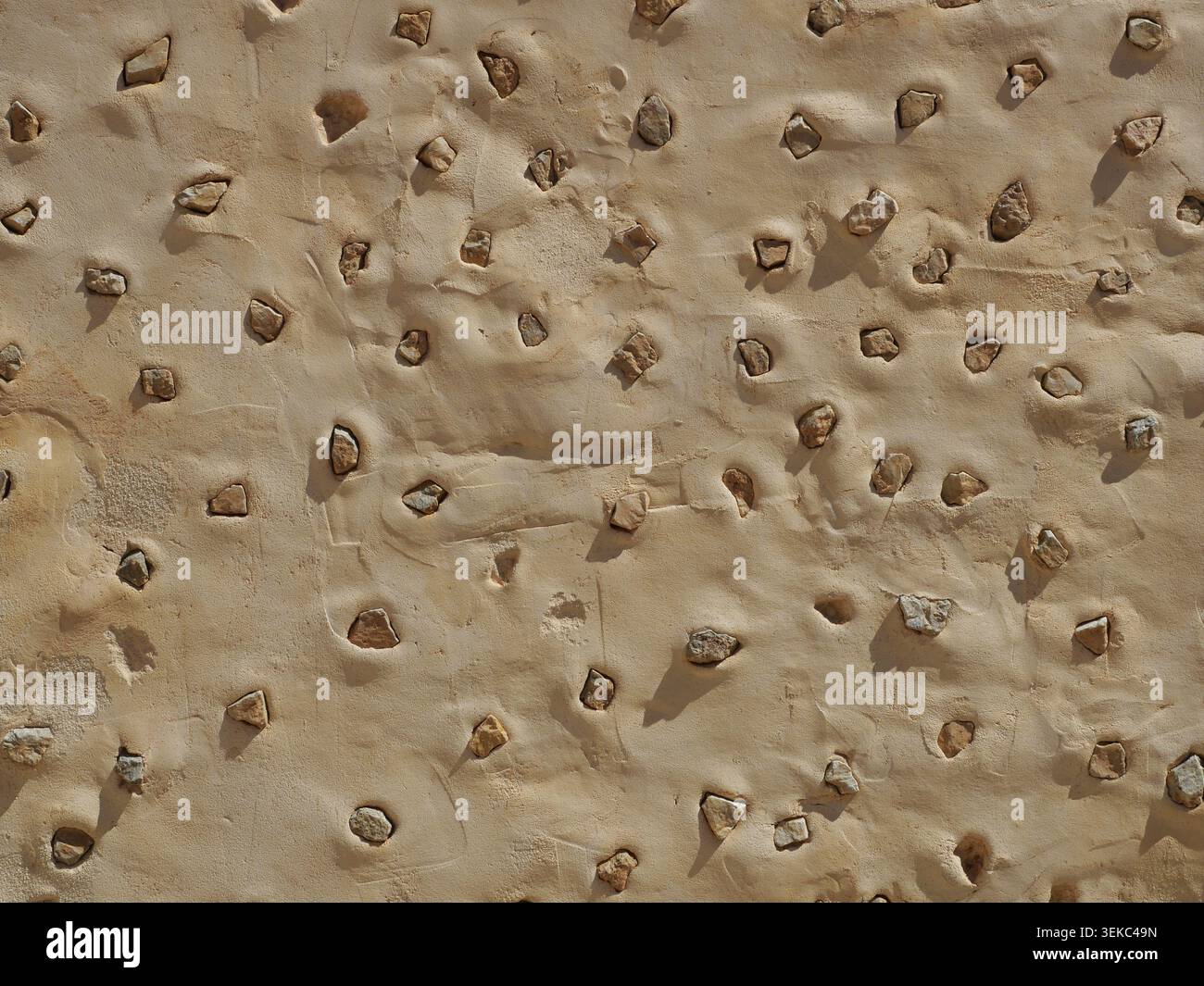 Mediterranean wall with embedded stones in plaster – repeating structure, ideal as background texture. Close-up. Copyspace. Stock Photo