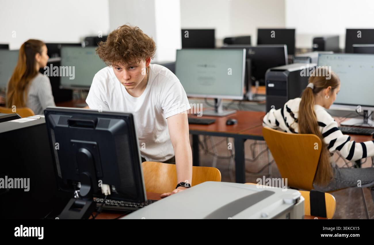 Focused teenager studying with classmates in computer lab Stock Photo