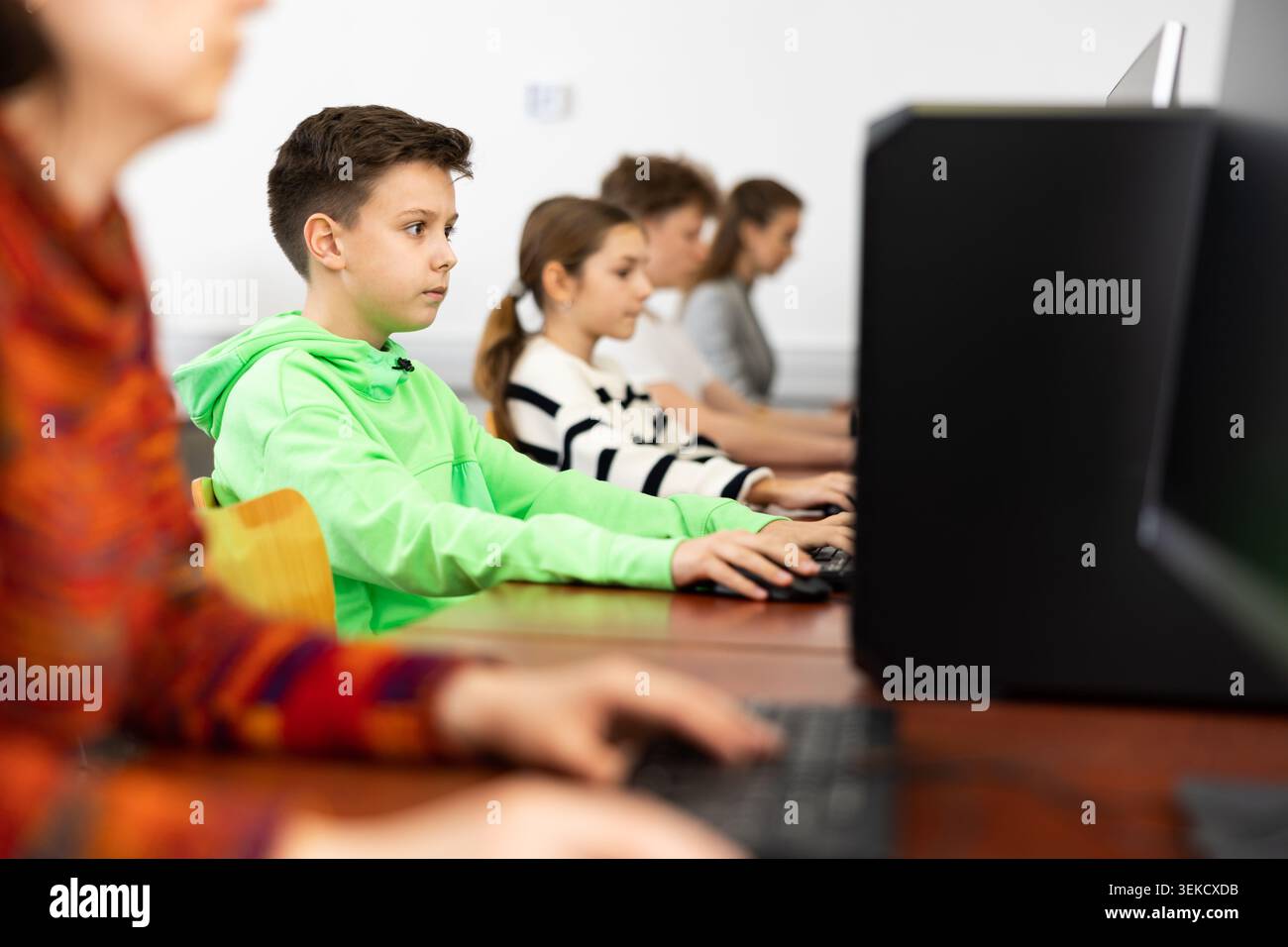 Pupils using computers at lesson, teacher teaching them in class room Stock Photo