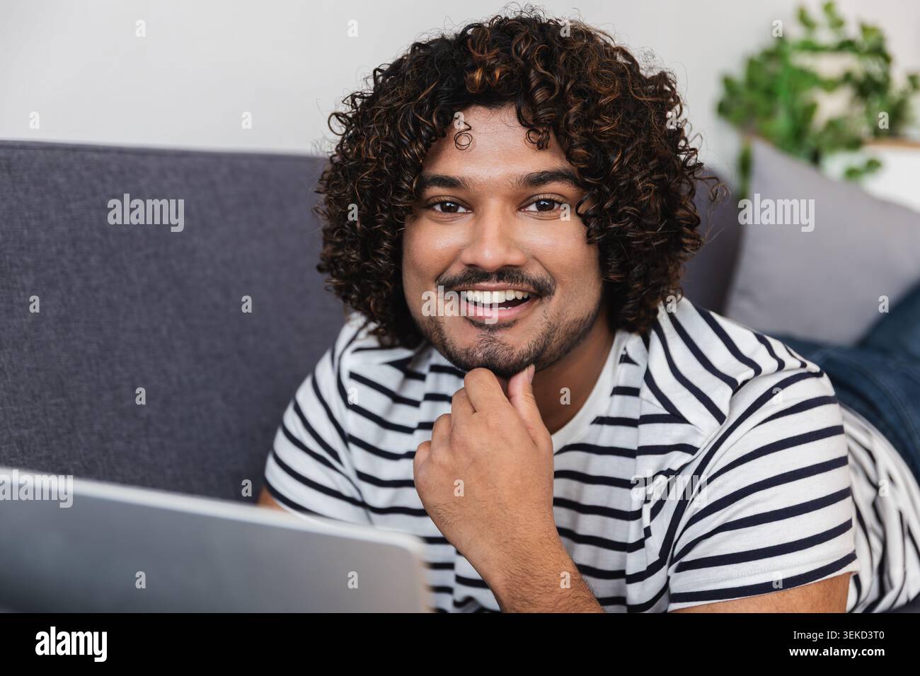 Young Indian man thinking while using laptop Stock Photo