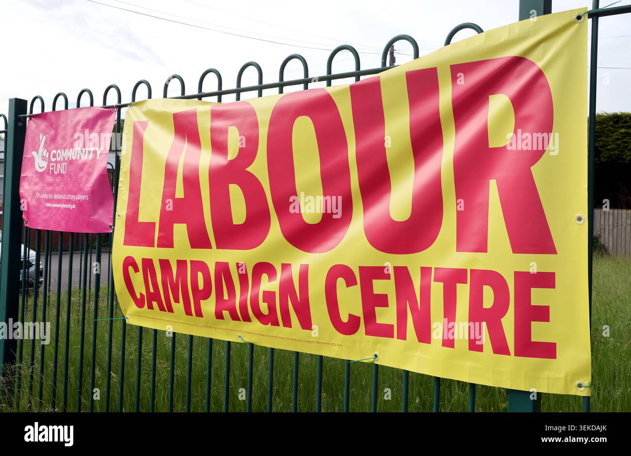 Large yellow Labour UK campaign HQ sign in Ashton-in-Makerfield, Wigan, Greater Manchester, with Community Fund banner nearby. Stock Photo