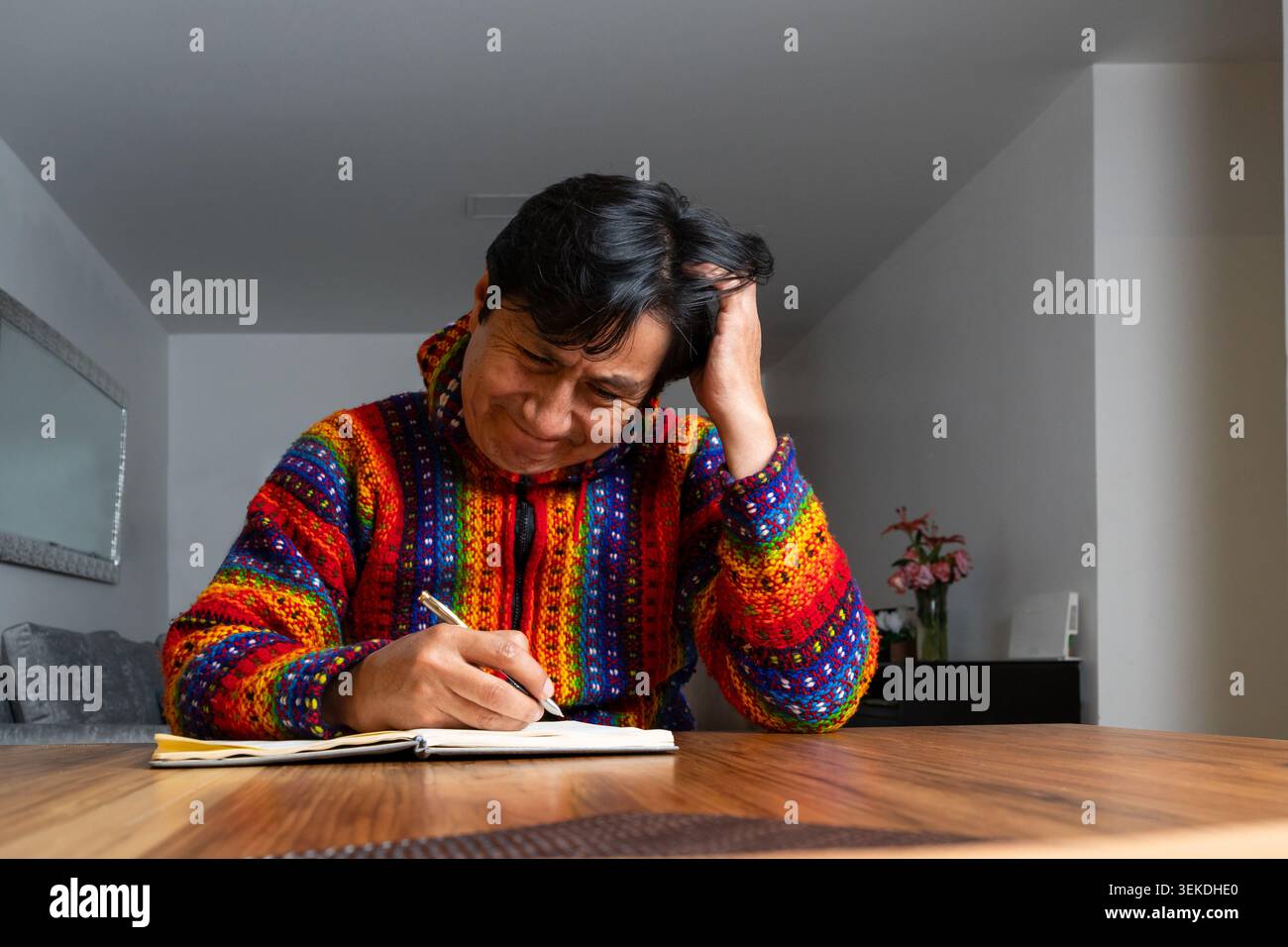 Man feeling frustrated while trying to write in his notebook at home Stock Photo