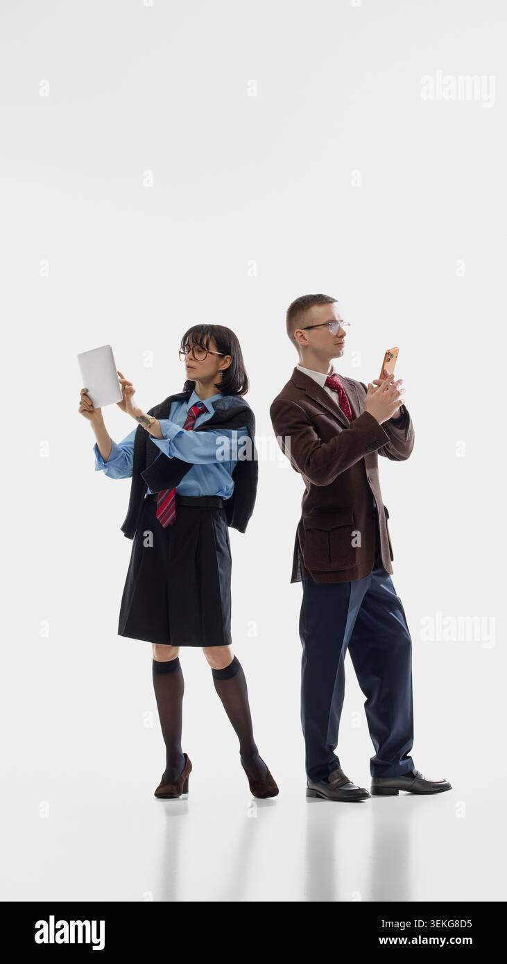 Business pair working on devices in white studio. Stock Photo