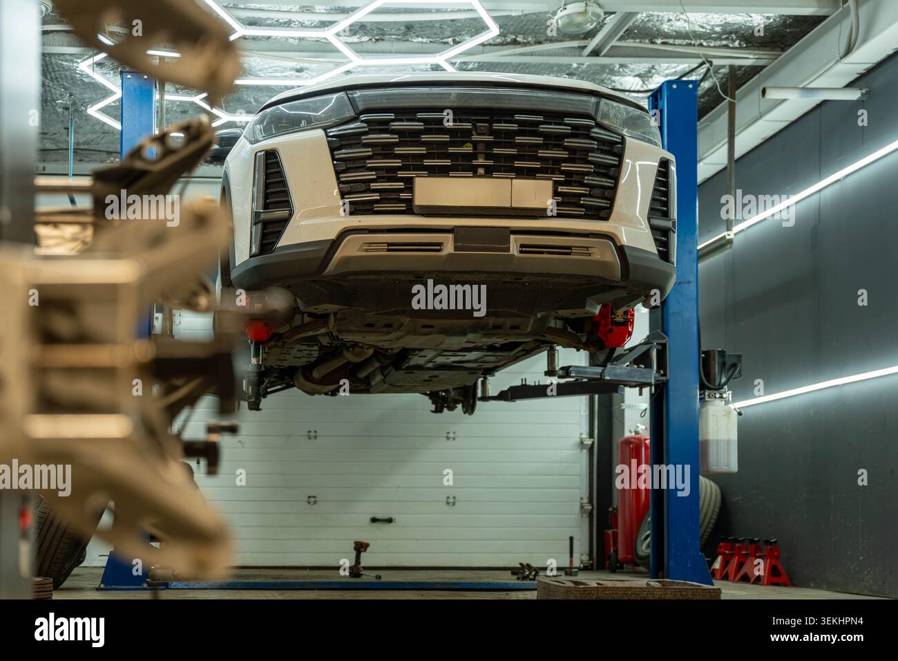 Modern SUV lifted for maintenance inside an automotive repair workshop ...