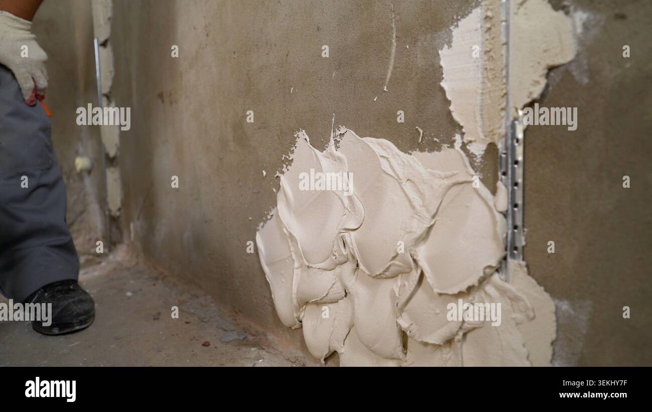 Construction worker applying plaster on wall using corner trowel Stock Photo