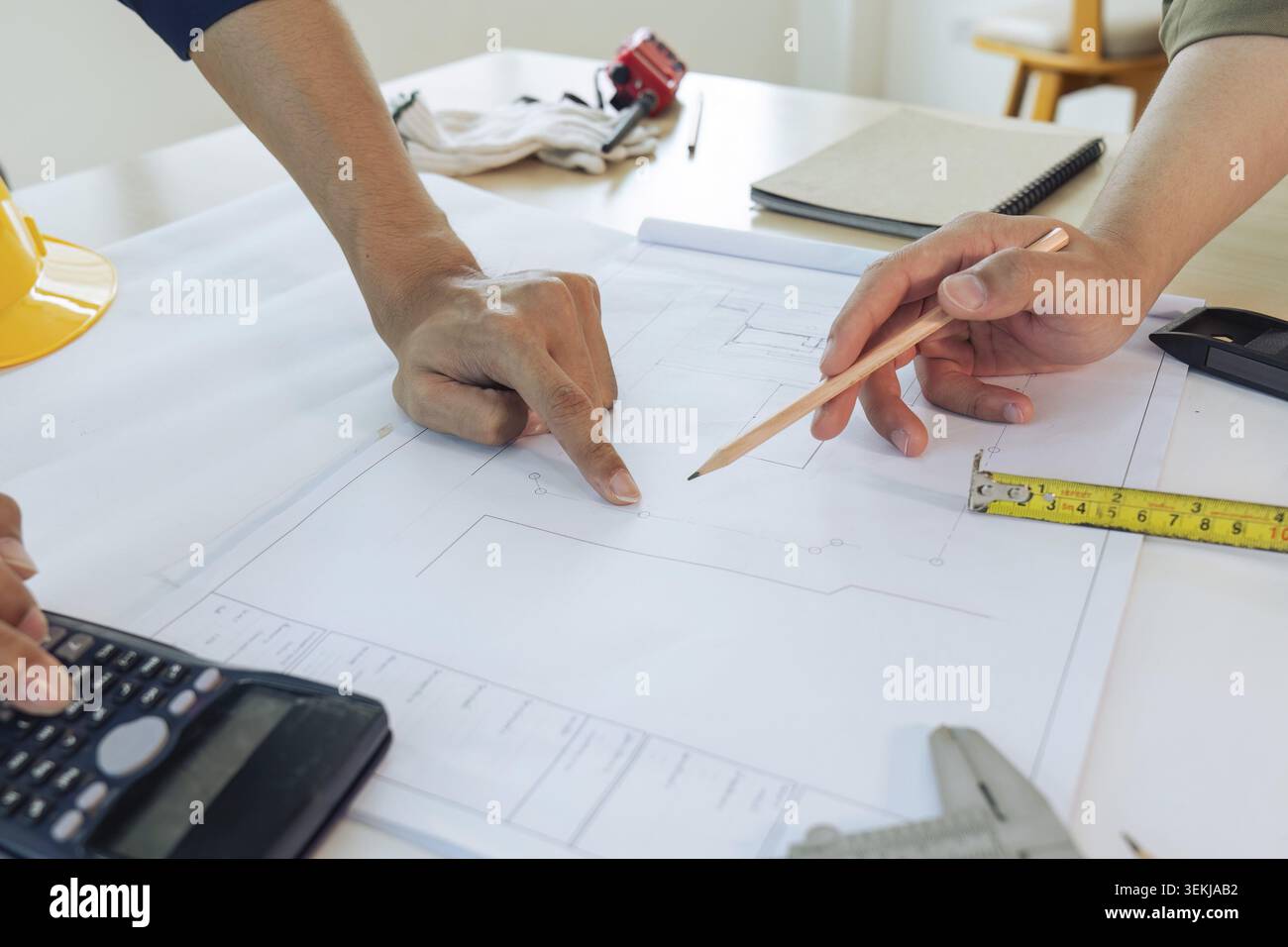 Architect man holding pencil working with blueprints for architectural plan Stock Photo