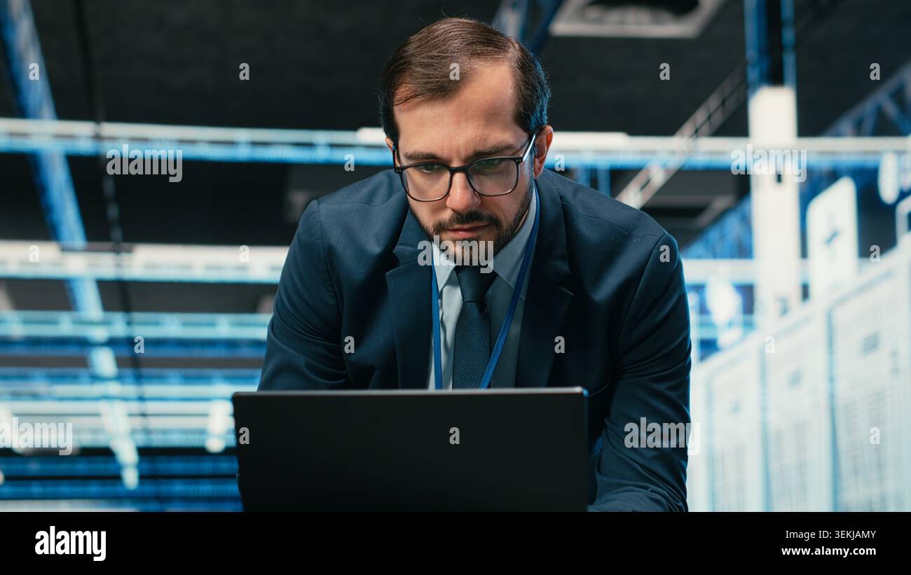 Data center admin typing on laptop keyboard, doing resource optimization using software. Server farm IT specialist using notebook program to upgrade hardware supercomputers, camera B Stock Photo