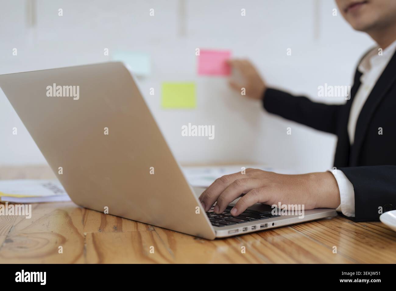 Businessperson working on laptop and typing on keyboard at table in office Stock Photo