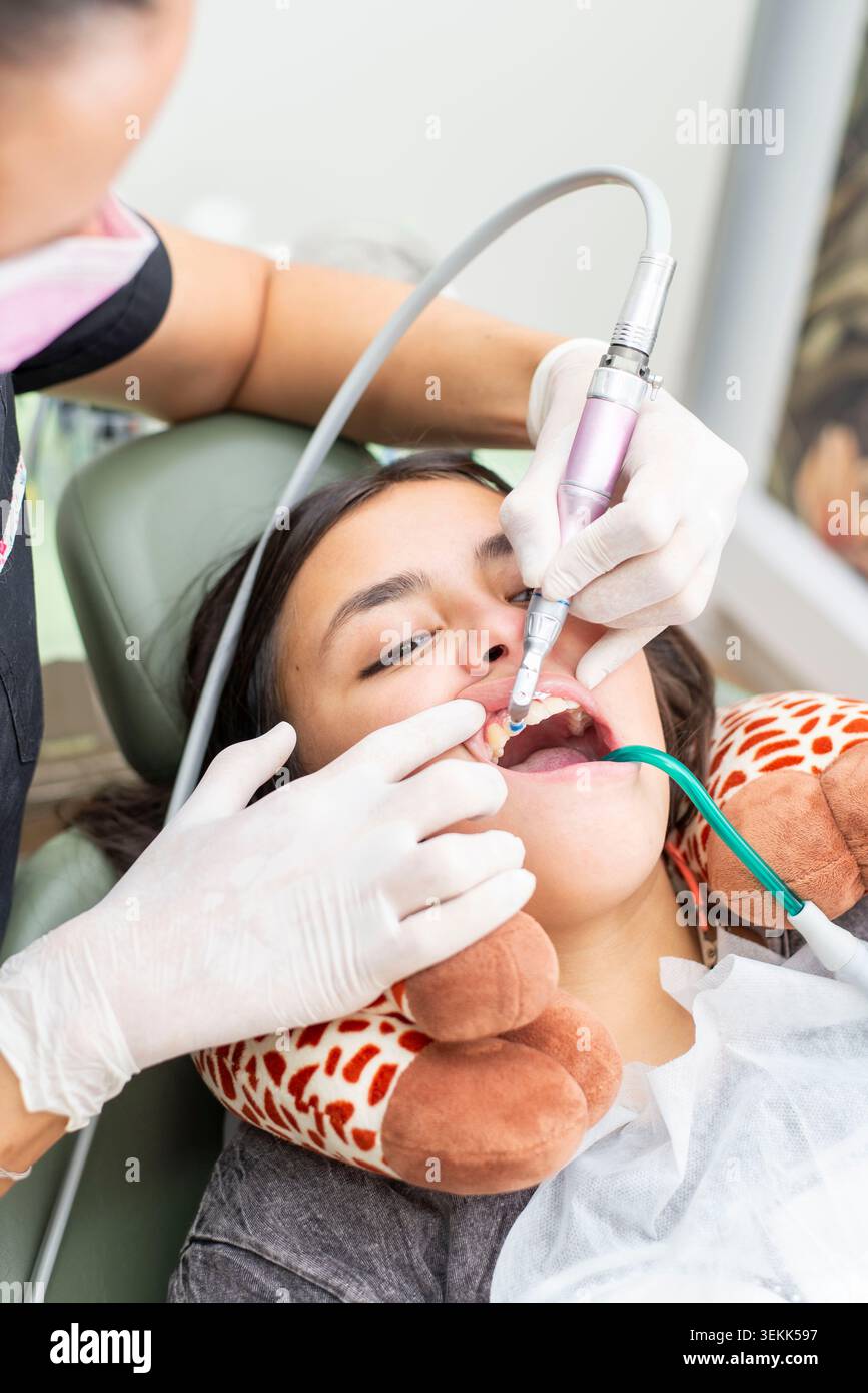 Dentist performing teeth cleaning on young patient teeth Stock Photo