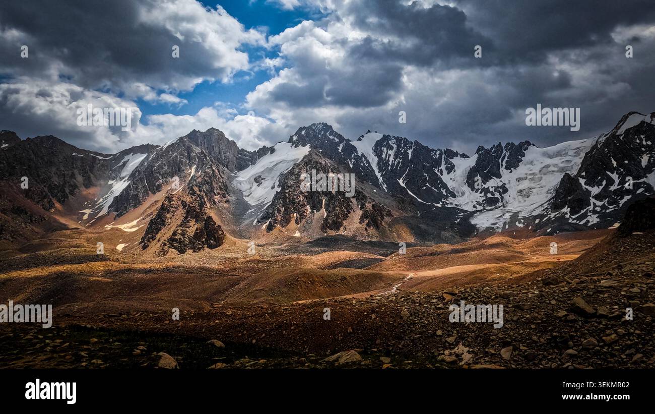 Dramatic Mountain Range with Tuyuk-Su Glacier and Stormy Clouds Stock Photo