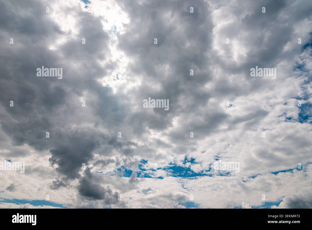 Dark storm clouds with sunlight breaking through dramatic sky background. Stock Photo