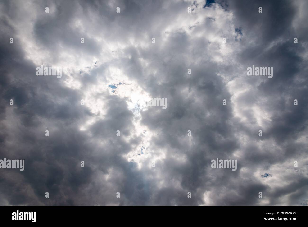 Dark storm clouds with sunlight breaking through dramatic sky background. Stock Photo