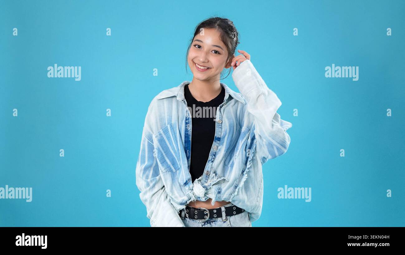 Smiling young asian woman touching her head with hand looking cheerful Stock Photo