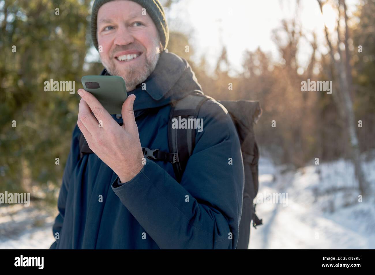 Smiling man talking through speaker phone while traveling in winter Stock Photo