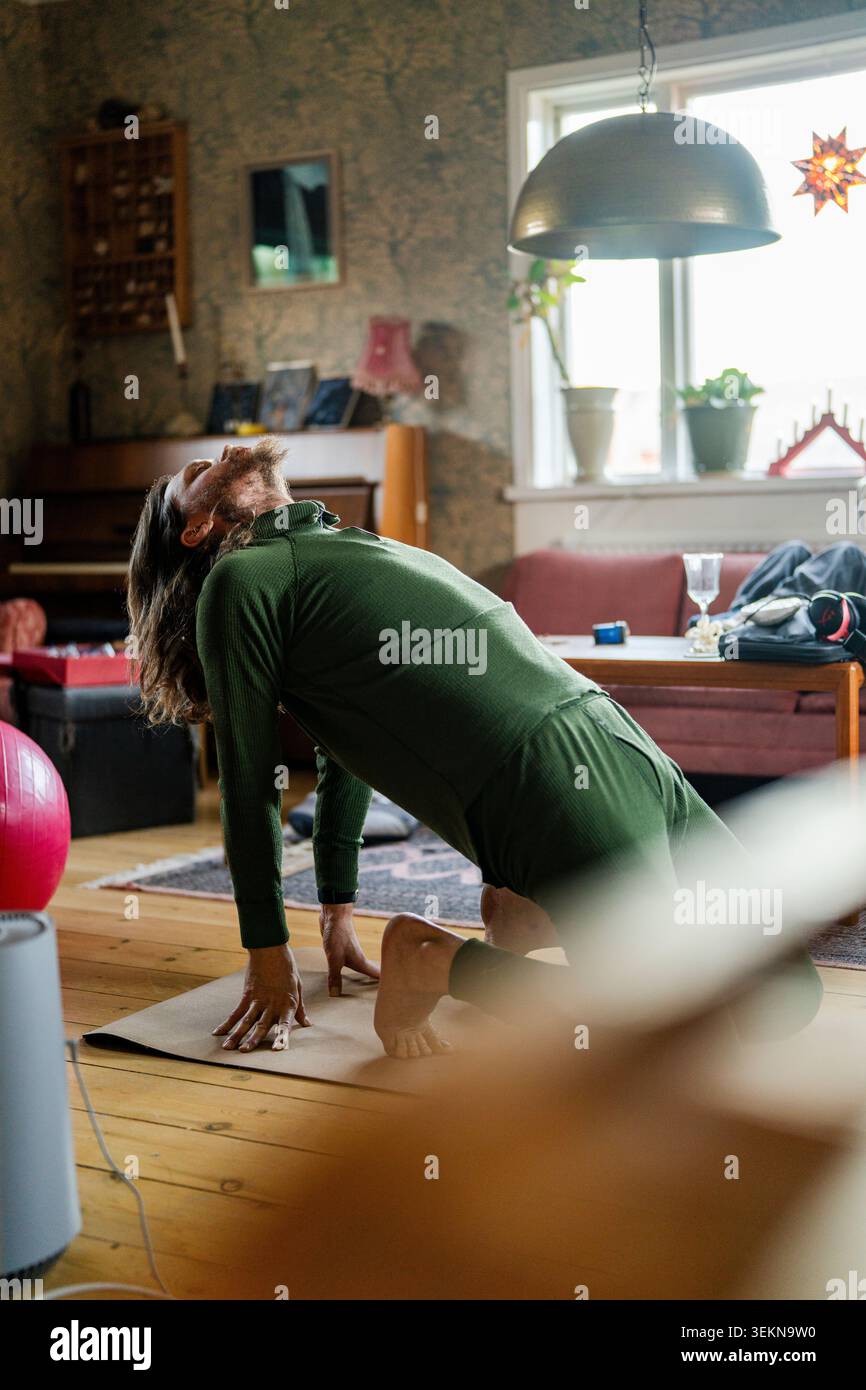 Active man doing camel pose on yoga mat at home Stock Photo