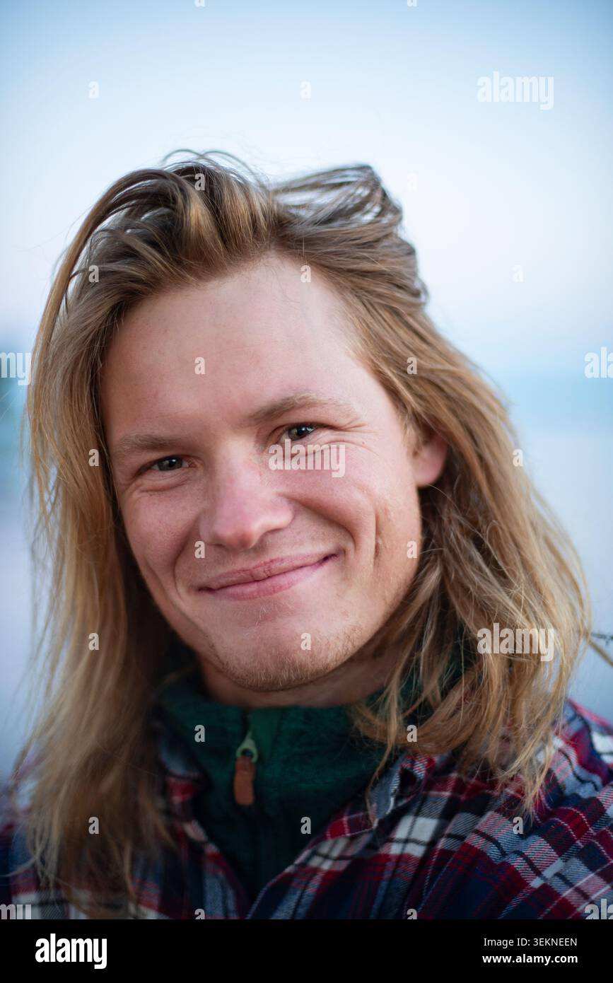 Portrait of smiling man with long blond hair Stock Photo