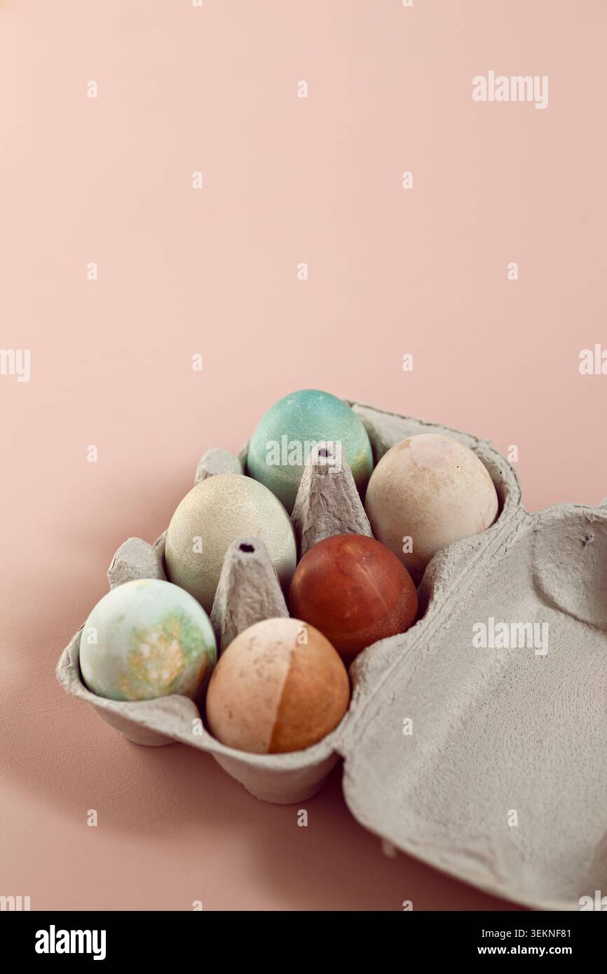 Colorful Easter eggs in egg box on beige surface Stock Photo