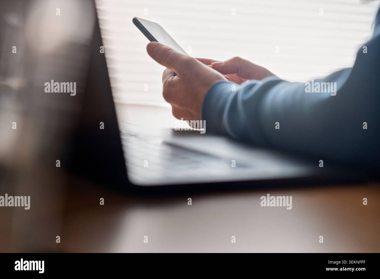 Freelancer using smart phone while sitting at desk Stock Photo