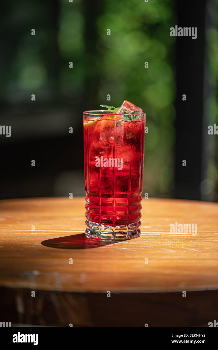Vibrant red cocktail with ice on table Stock Photo